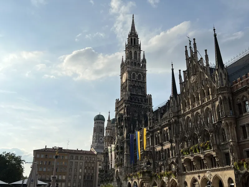München: der Turm des Neuen Rathauses am Marienplatz, dahinter eine Kuppel der Frauenkirche